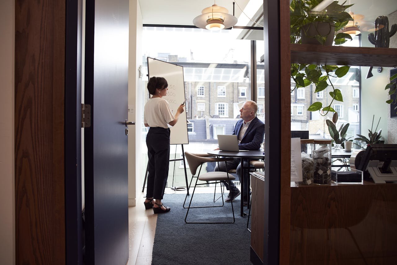 about-us-01 Colleagues engage in a strategic business meeting in a contemporary London office with city views.
